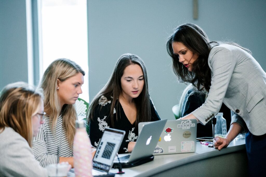 A faculty member working with students together on their laptops